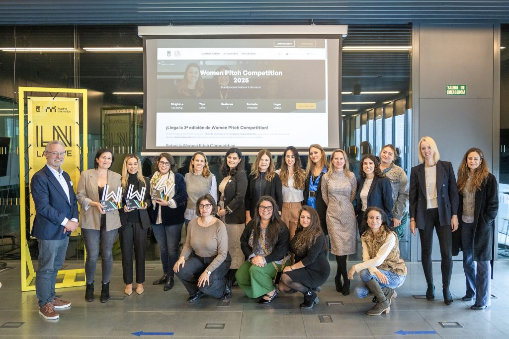Mujeres innovadoras reunidas en una sala con pantalla de fondo